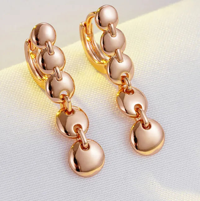 A pair of long, round, gold-toned retro earrings with a woven copper design.