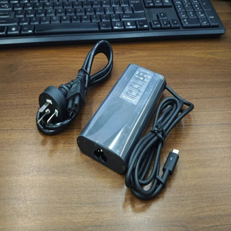 Black 65W USB-C laptop power adapter with a set of international plug cords for UK, US, EU, AU and SA sockets.