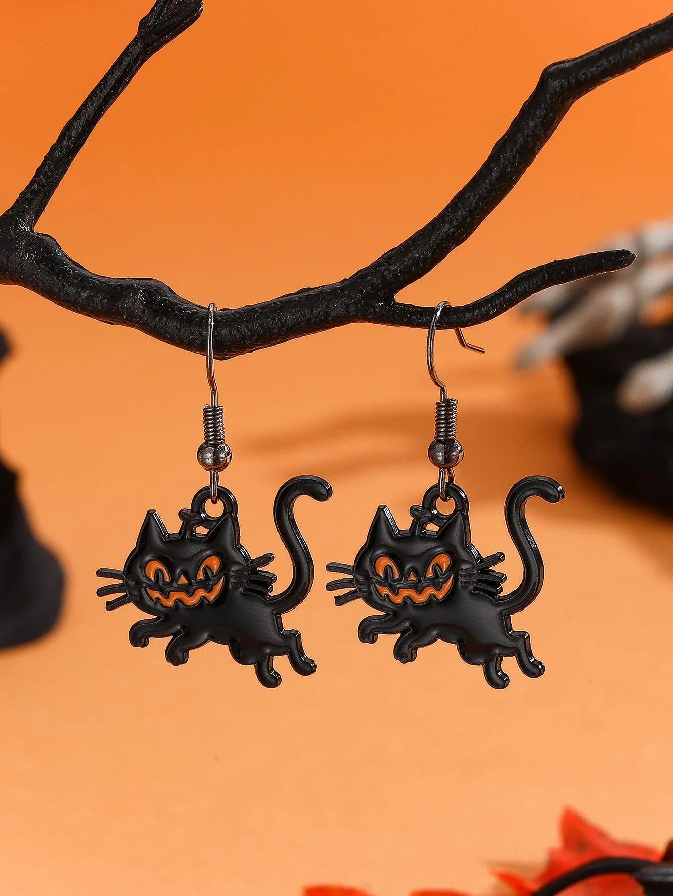 Set of six Halloween earrings with bat, cat, pumpkin head, skeleton, spider, and witch motifs on a dark background