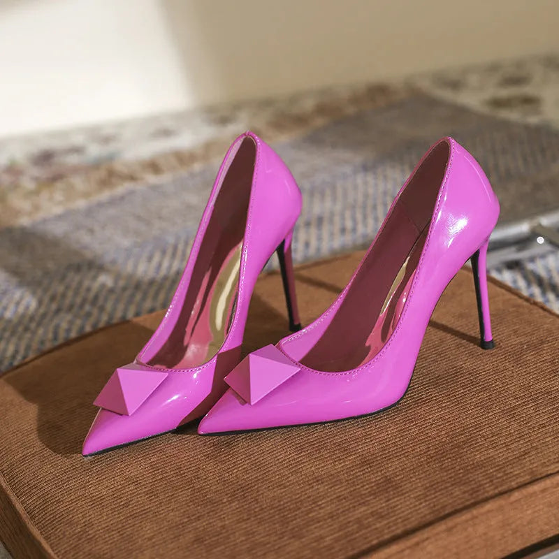 Pink patent leather women's pointed toe stiletto high heels with a buckle.