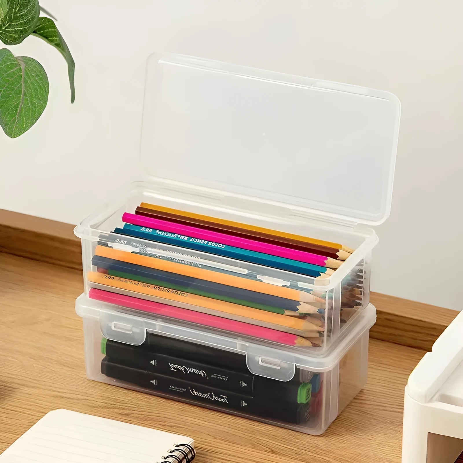 Transparent plastic stationery storage box containing pencils and colour crayons