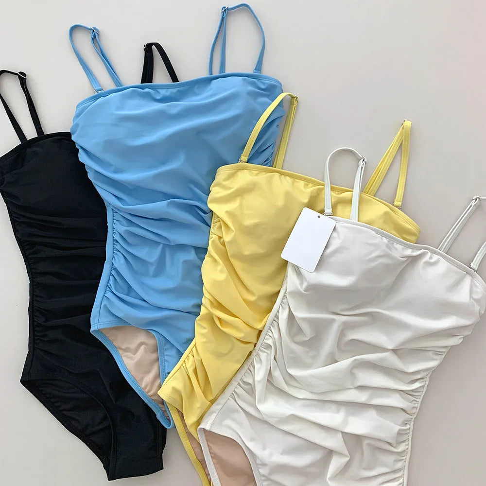 Blue sling style one-piece swimsuit with belly pleats on a mannequin.