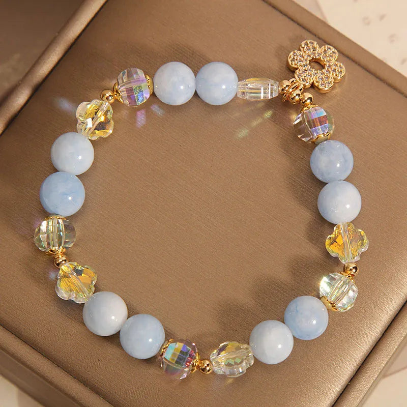 Women's aquamarine crystal bracelet featuring a four-leaf clover charm and pearl decorative elements.