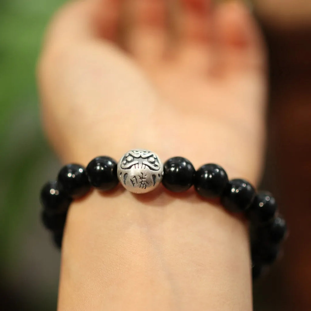 Close-up of a women's bracelet with spherical black agate beads and a shiny sterling silver clasp on a wrist.