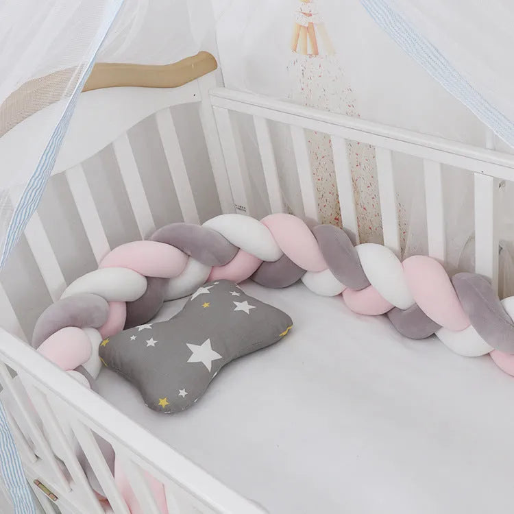 Braided knot baby crib bumper in spandex velvet wrapped around white cot rails.
