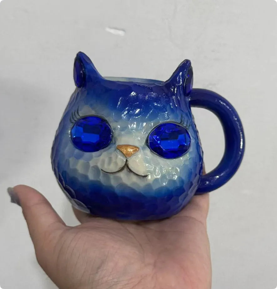 Colourful cat-shaped resin craft ornament in purple, green, blue, or pink on a desk.