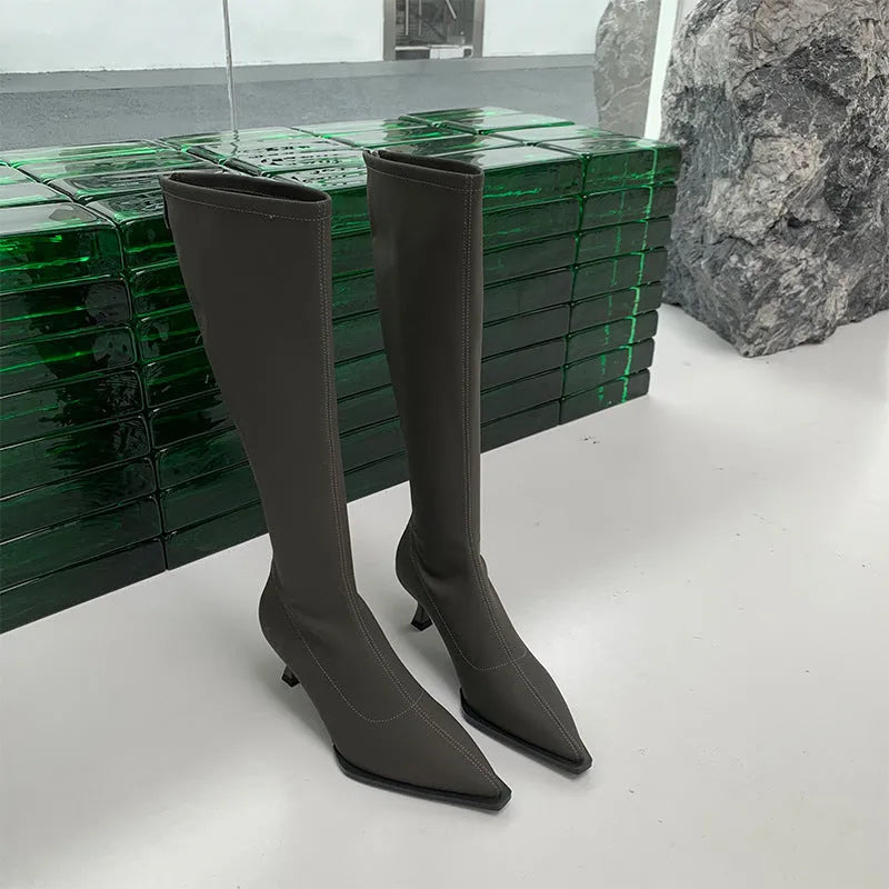Women's black pointed toe stiletto heel boots with a back zipper, shown below the knee.