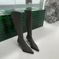 Women's black pointed toe stiletto heel boots with a back zipper, shown below the knee.