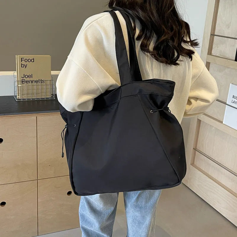 Soft folding shoulder tote bag in Oxford cloth shown in one of five colour options: black, brown, dark grey, light grey, or purple.