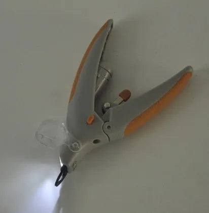White dog nail clipper with LED light, safety guard, and three LR44 batteries on a blister card.
