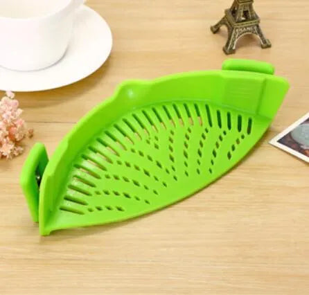 Silicone clip-on funnel strainer attached to a pot rim, showing hollow design and stainless steel buckle.