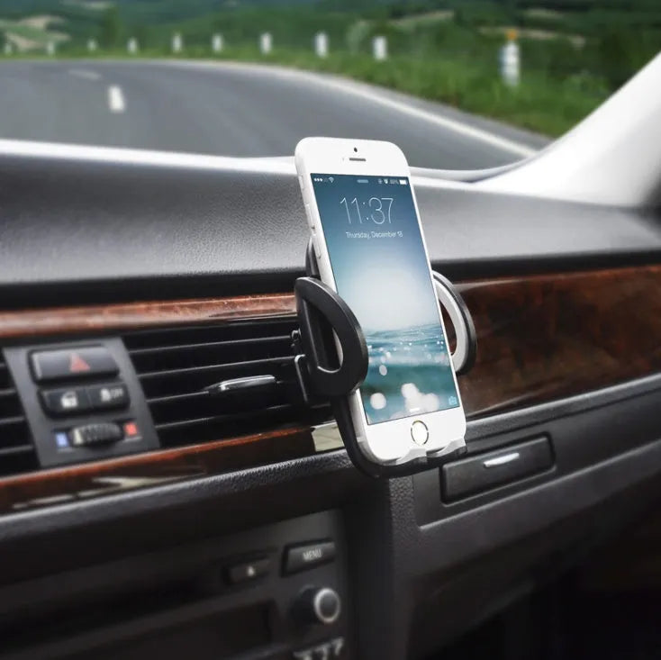 Black plastic car mobile phone holder mounted on air conditioning vent with adjustable arms gripping smartphone