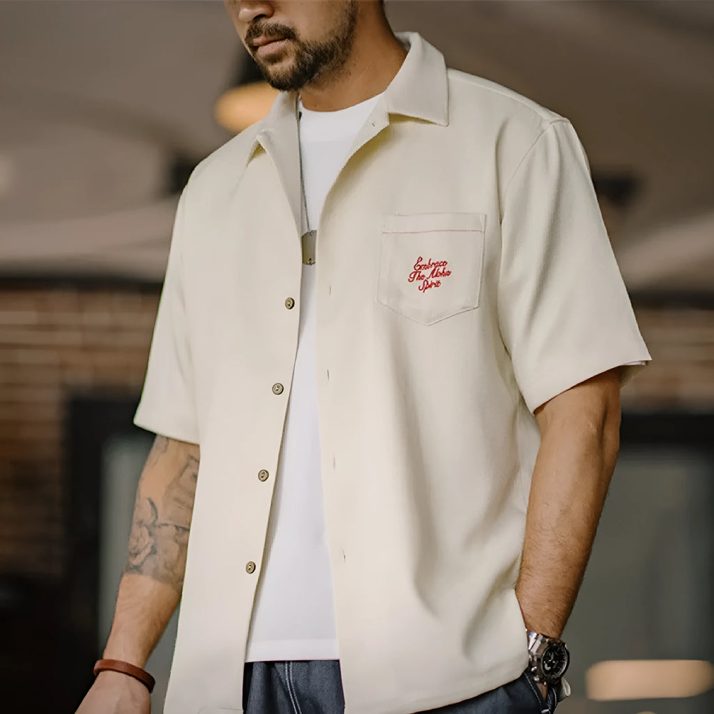 Light apricot men's shirt with bamboo plant print and a Cuban collar on a hanger