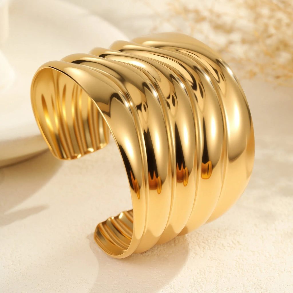 Women's wide stainless steel bracelet with 18K gold plating, geometric wave design, and niche opening closure.