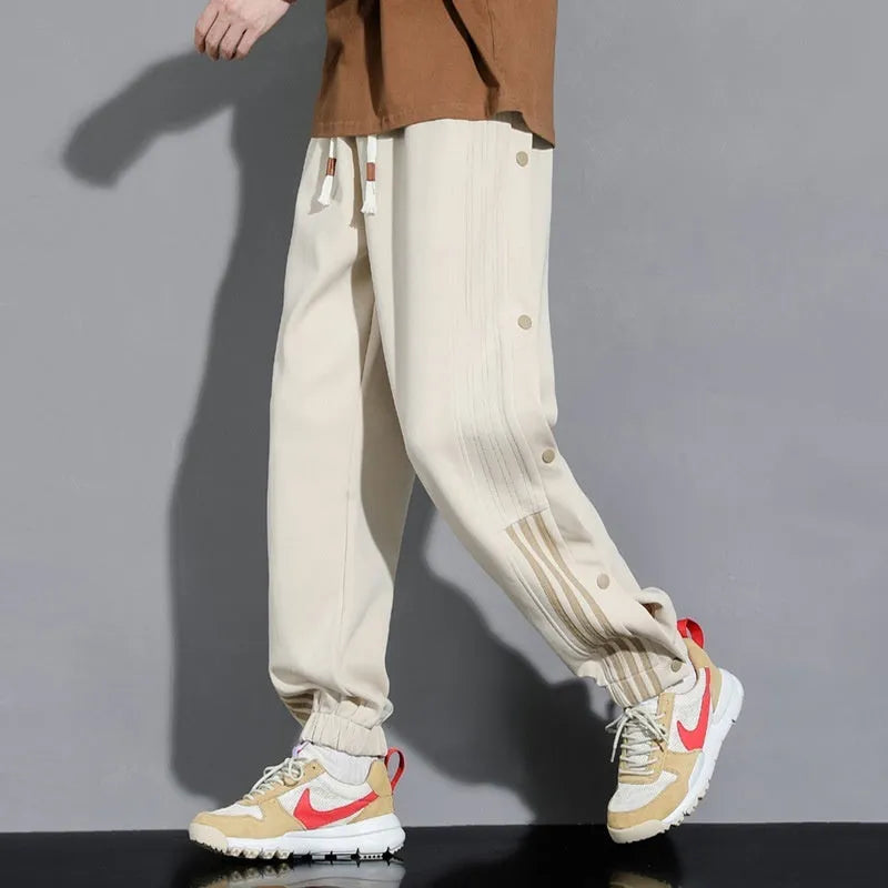 Men's black high-waist sweatpants with ankle-tied cuffs and a drawstring waist on a grey background.