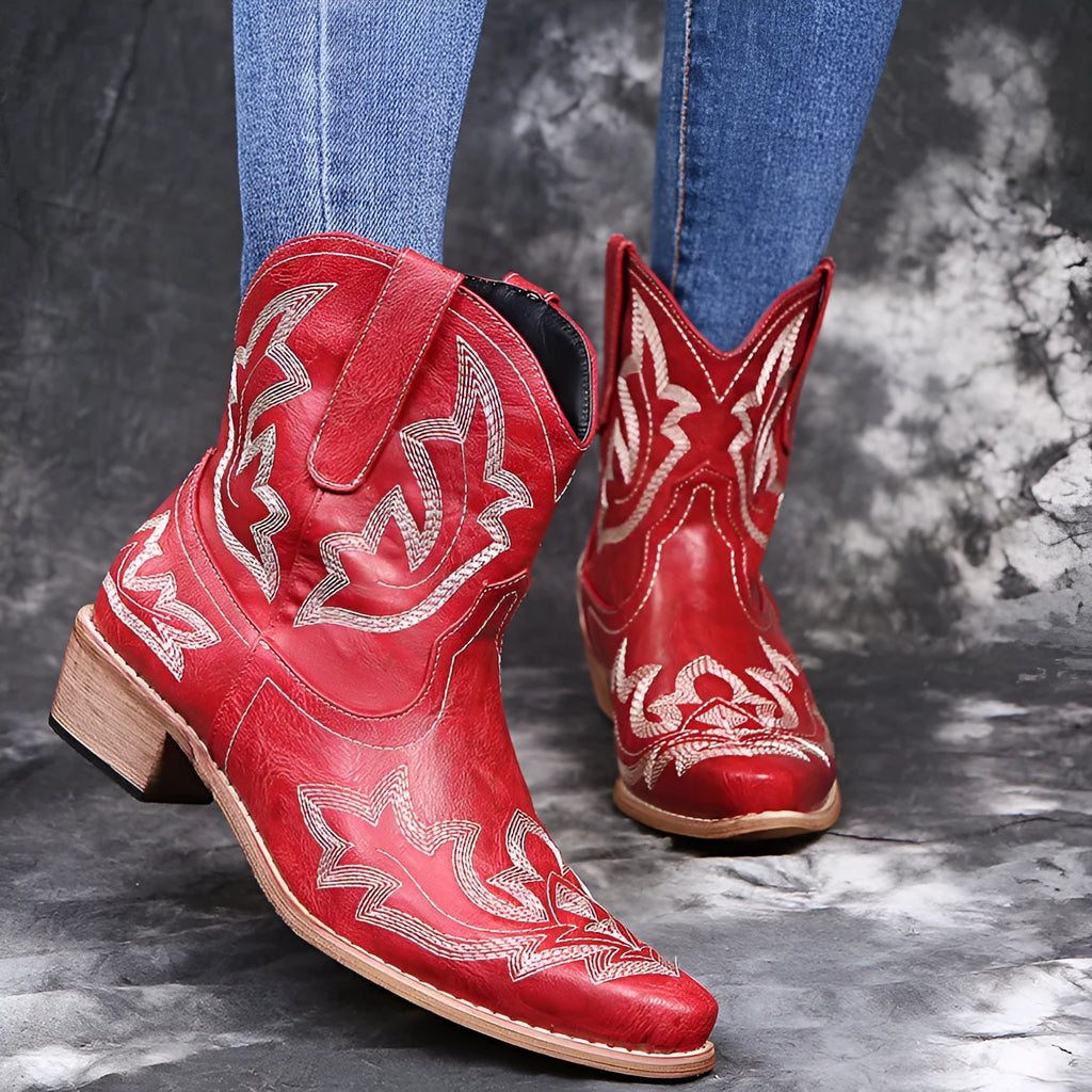 Blue women's cowboy boots with embroidery and a low wedge heel on a wooden floor.