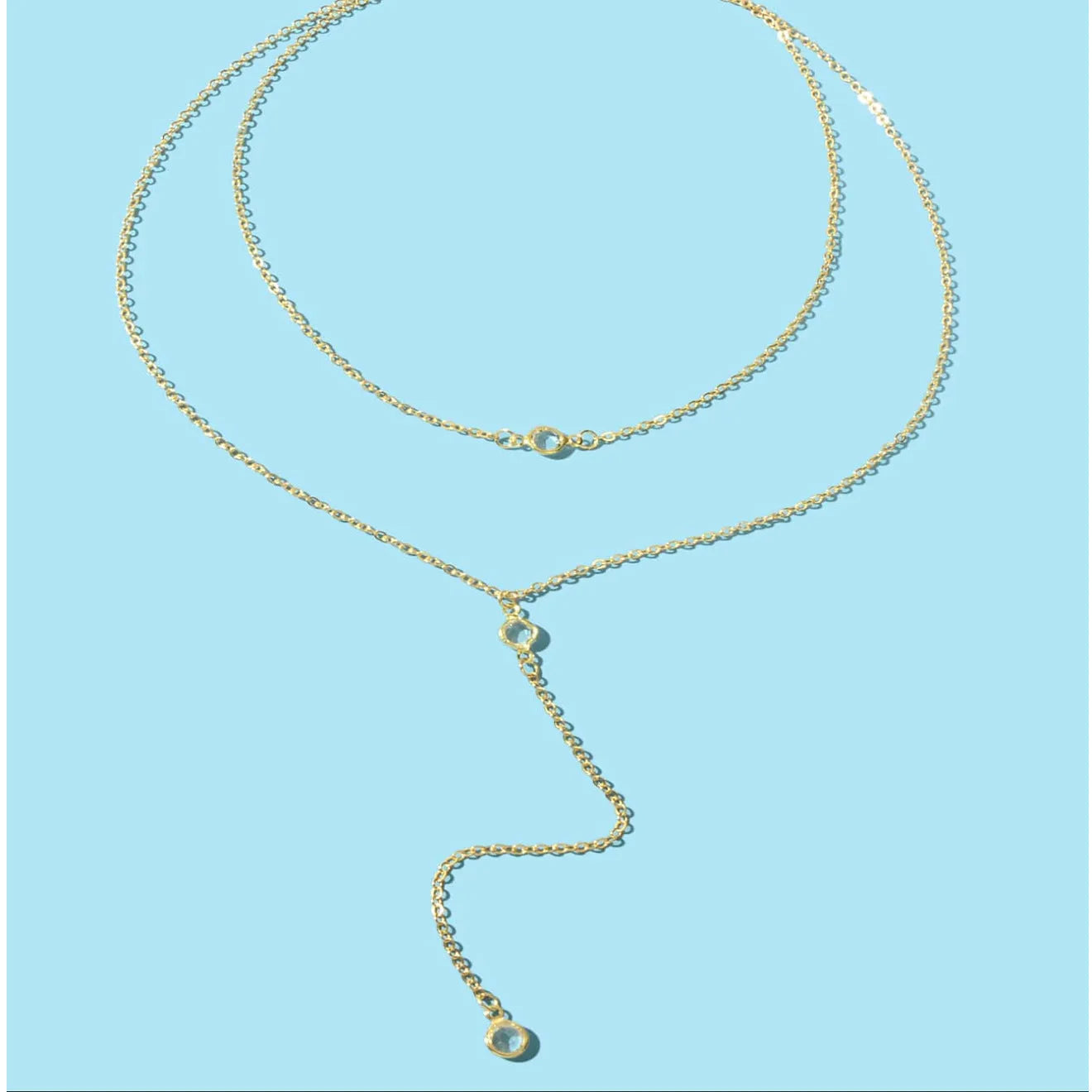 Female gold alloy O-ring chain necklace with geometric pendant on a light background