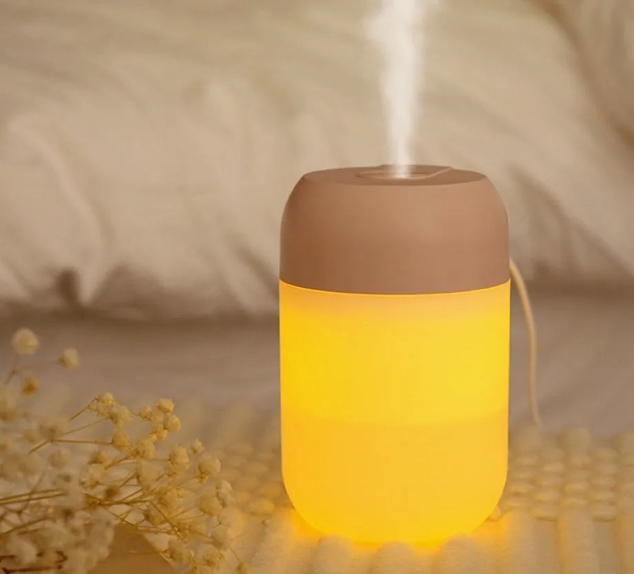 Small white cylindrical USB humidifier with aromatherapy function on a desk.
