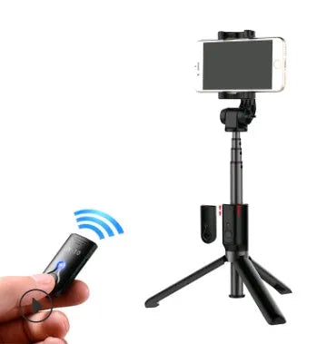 Aluminium Bluetooth selfie stick with tripod base and remote control next to a smartphone.