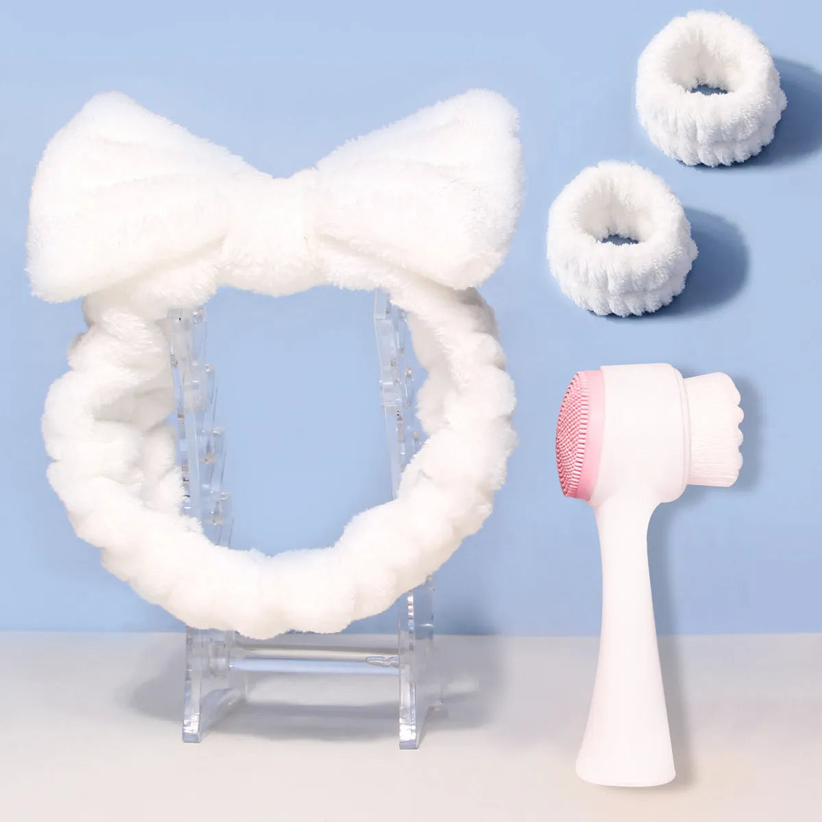 Facial brush with plastic handle and nylon bristles alongside coral fleece absorbent hair band in purple colour