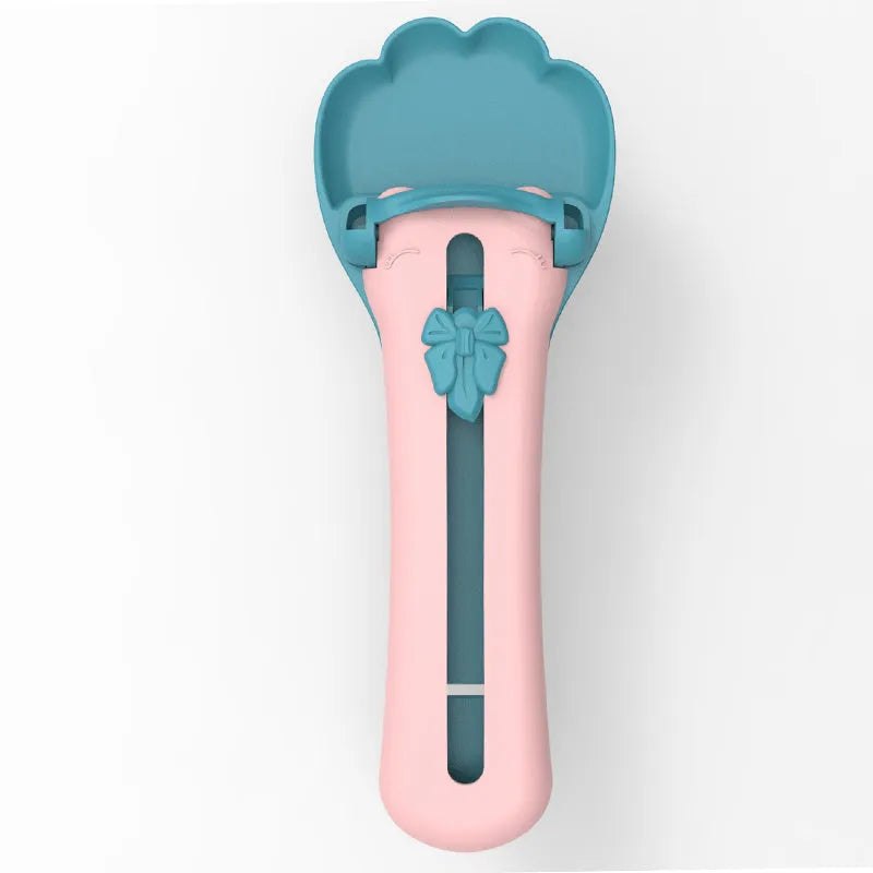 Green and pink pet food squeezer scoop dispensing a treat for a cat or dog.