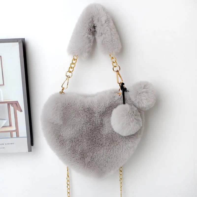 A soft, heart-shaped plush handbag for women in a medium size with a detachable shoulder strap.