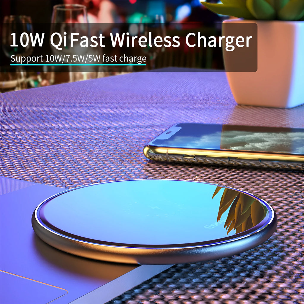 Black 15W fast wireless charging pad on a wooden desk next to a smartphone.