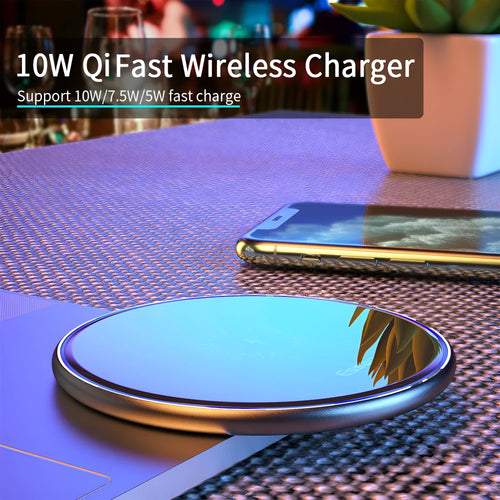 Black 15W fast wireless charging pad on a wooden desk next to a smartphone.