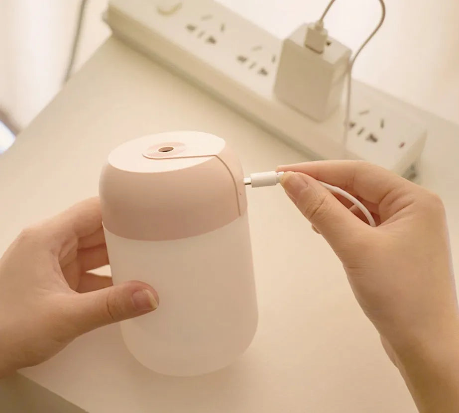 Small white cylindrical USB humidifier with aromatherapy function on a desk.