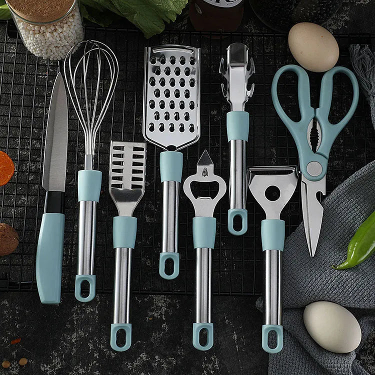 Stainless steel kitchen gadget set with whisk, grater, peeler, fruit knife, scissors, and tray lifter in grey
