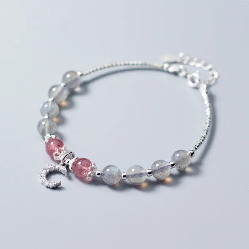 Handmade adjustable bracelet with a natural moonstone and silver crescent moon charm on a wrist.