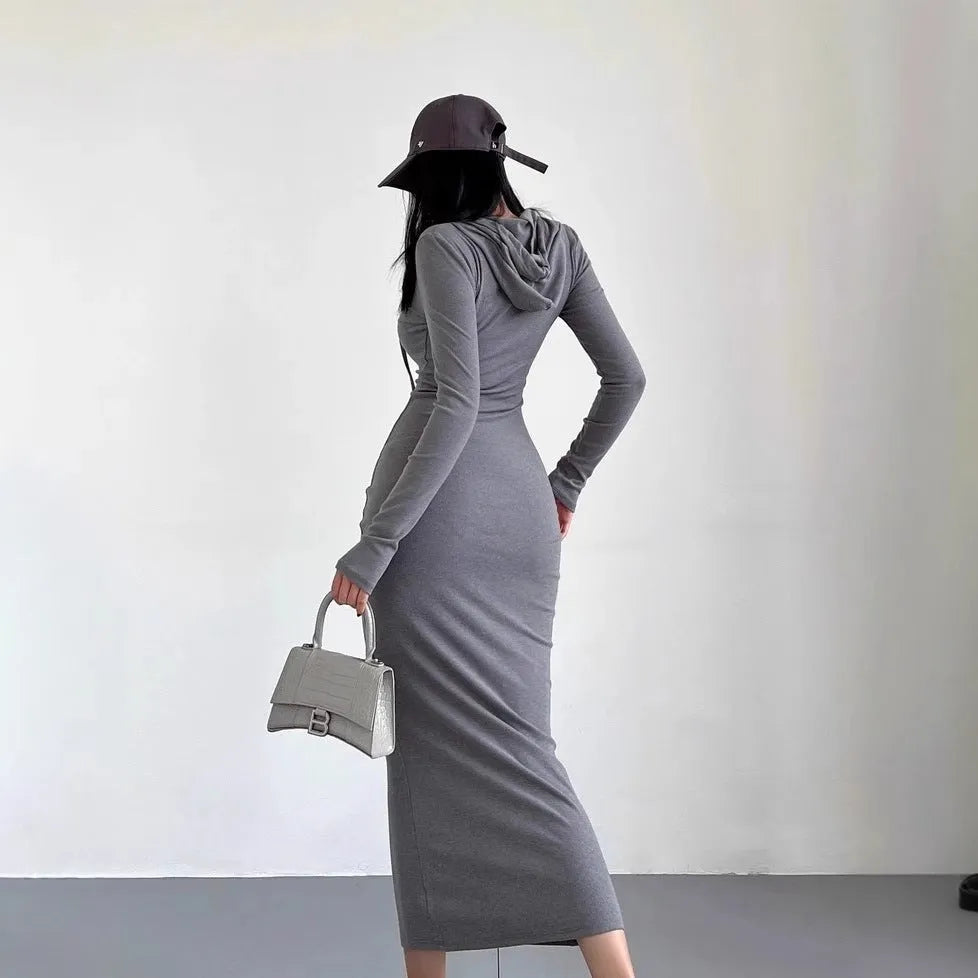 A woman wearing a light grey hooded sheath dress with long sleeves, showcasing the high waist and over-the-knee length.