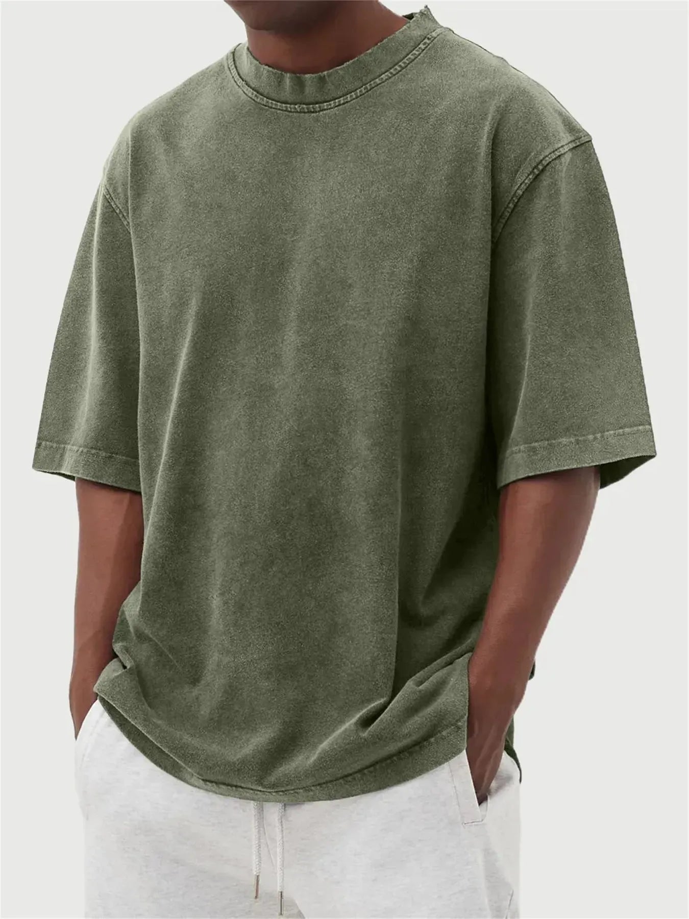 Man wearing a loose-fit, stone-washed grey t-shirt with a distressed solid colour finish and half sleeves.
