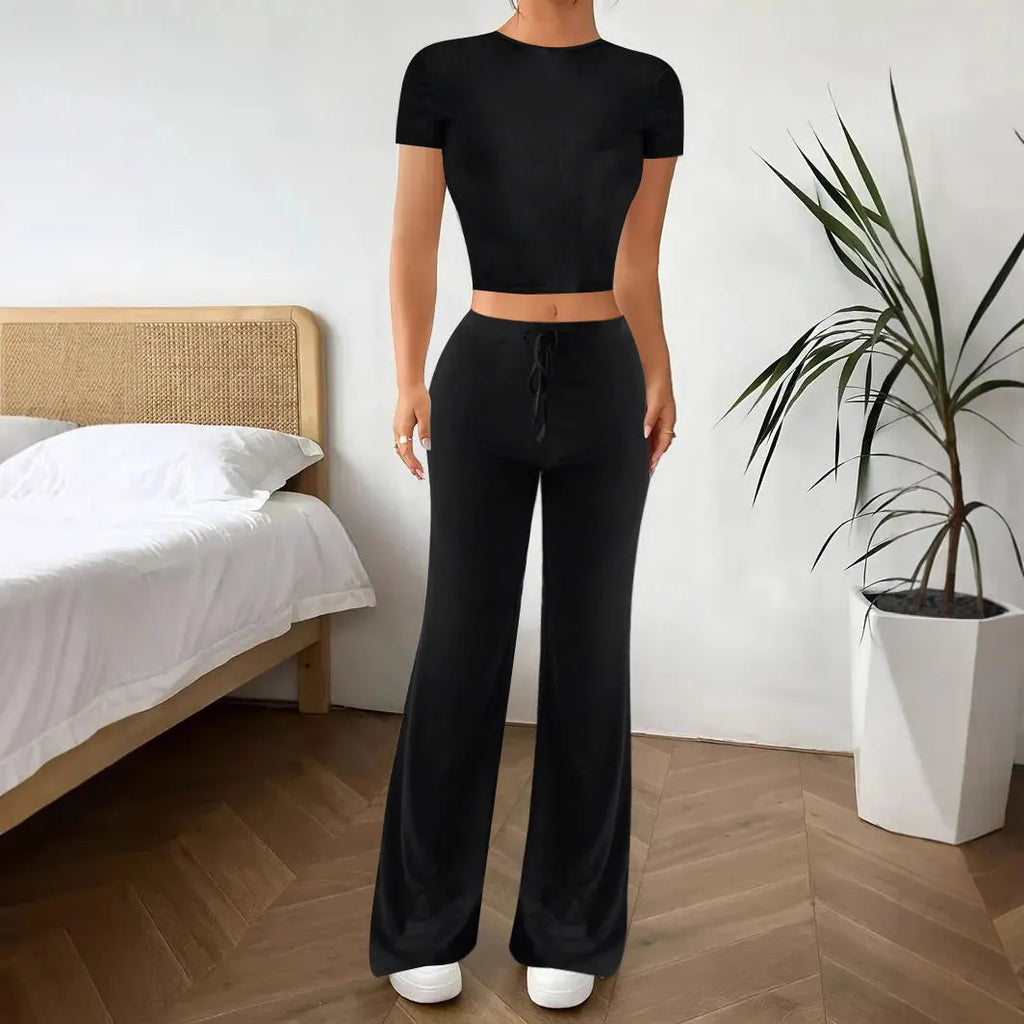 Black women's high waist trousers and short sleeve t-shirt co-ord set laid flat.
