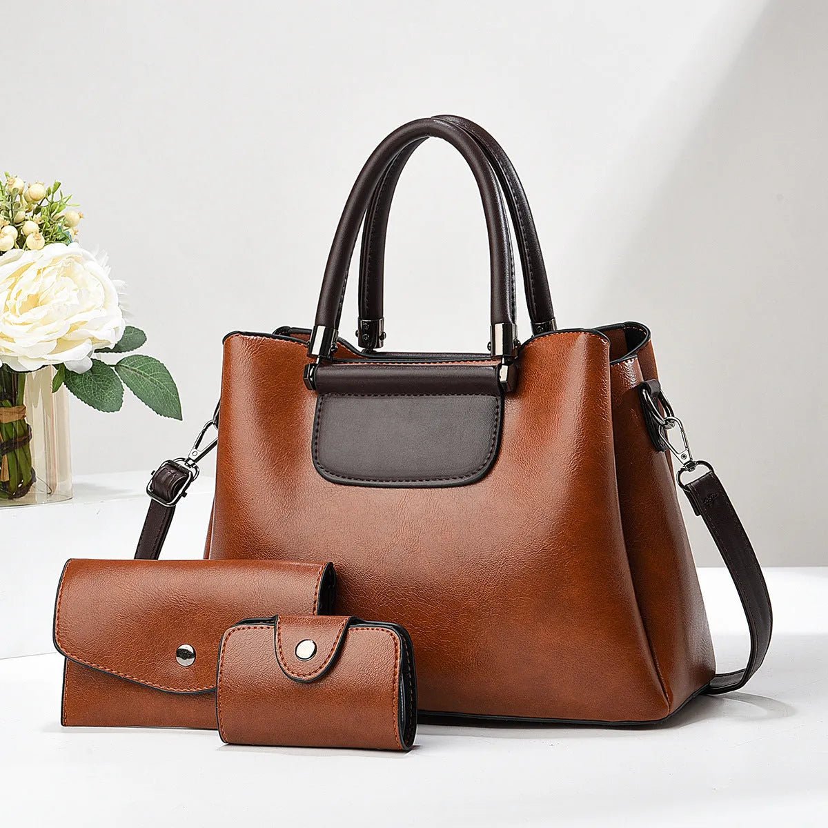 Large PU leather handbag set in horizontal square shape with matching medium and small pouches on white background