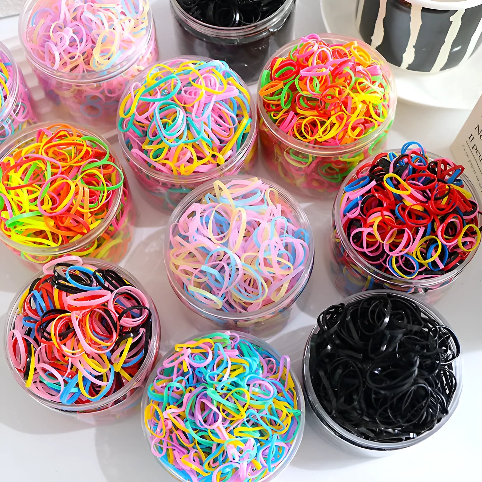 Multi-colour TPU baby hair ties for toddlers stored in a reusable clear container.