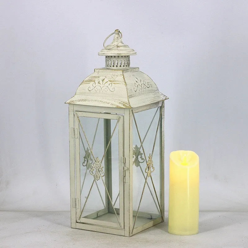 Black wrought iron floor lantern with glass panels on a stone patio.