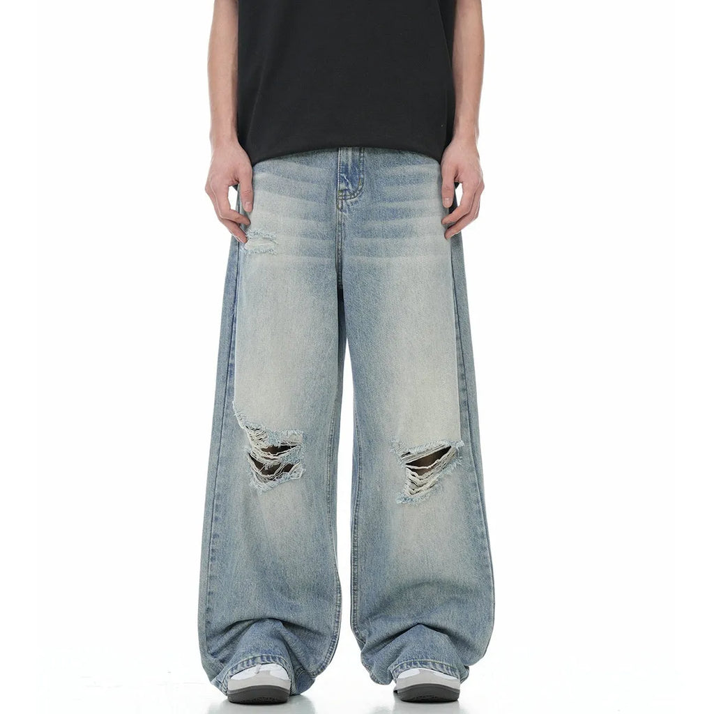 Blue men's straight-leg jeans with ripped distressing on the thigh, showing five-pocket design and zip fly.