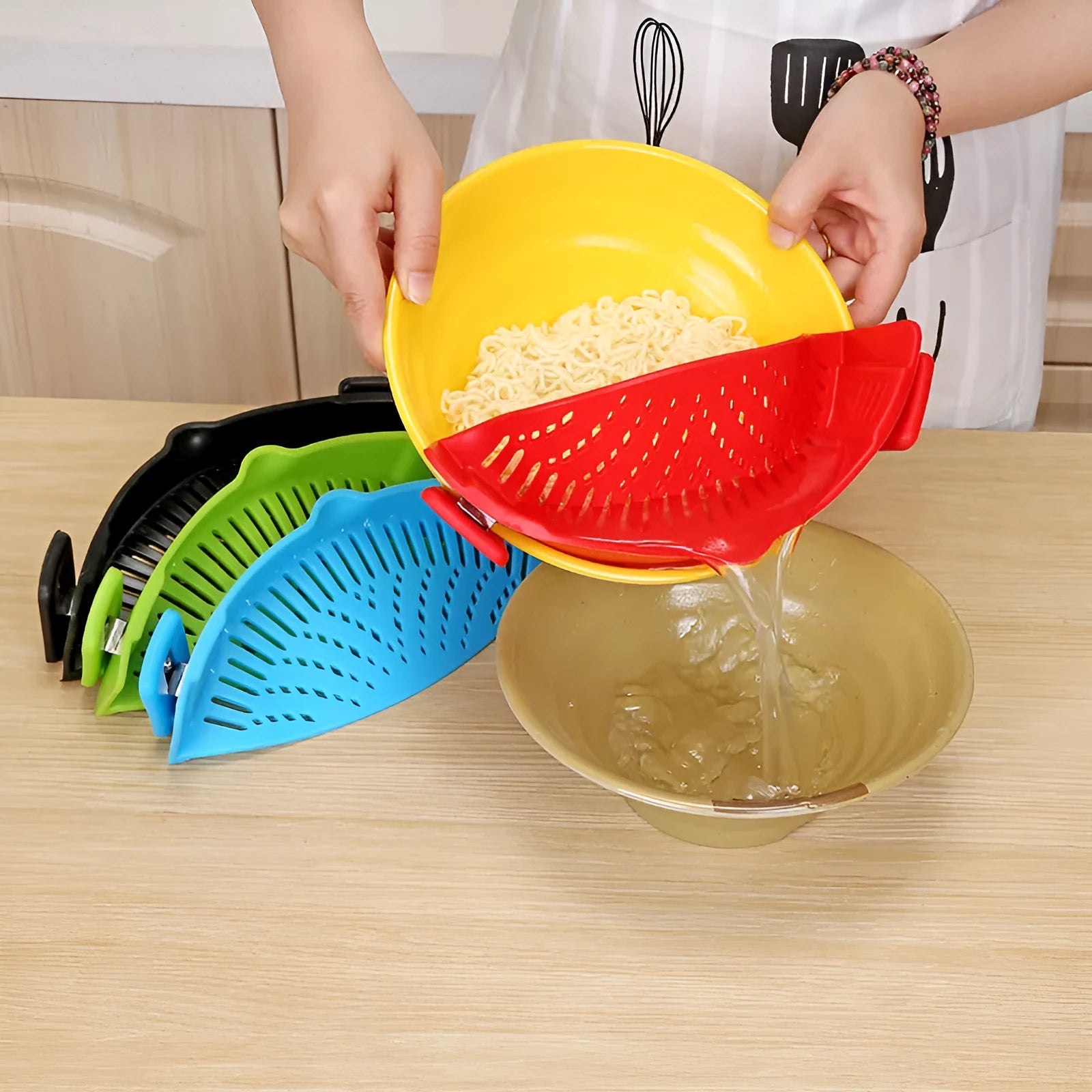Silicone clip-on funnel strainer attached to a pot rim, showing hollow design and stainless steel buckle.
