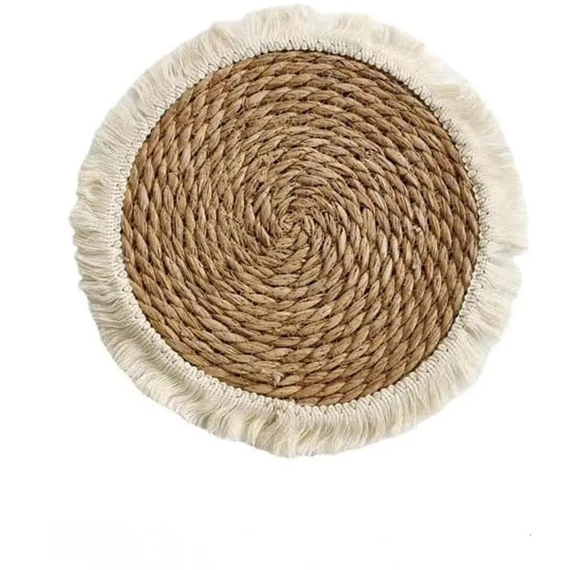 Round natural papyrus placemat with tassel trim on a wooden table.