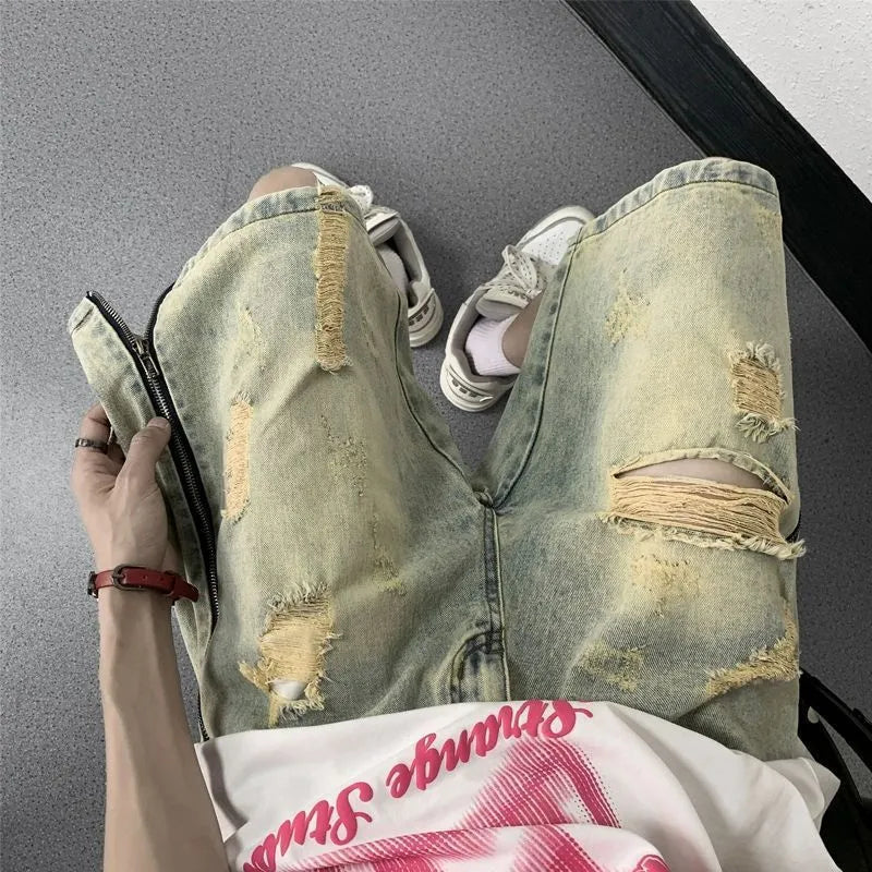 Man wearing blue distressed denim shorts with rips and a loose, straight-leg silhouette.