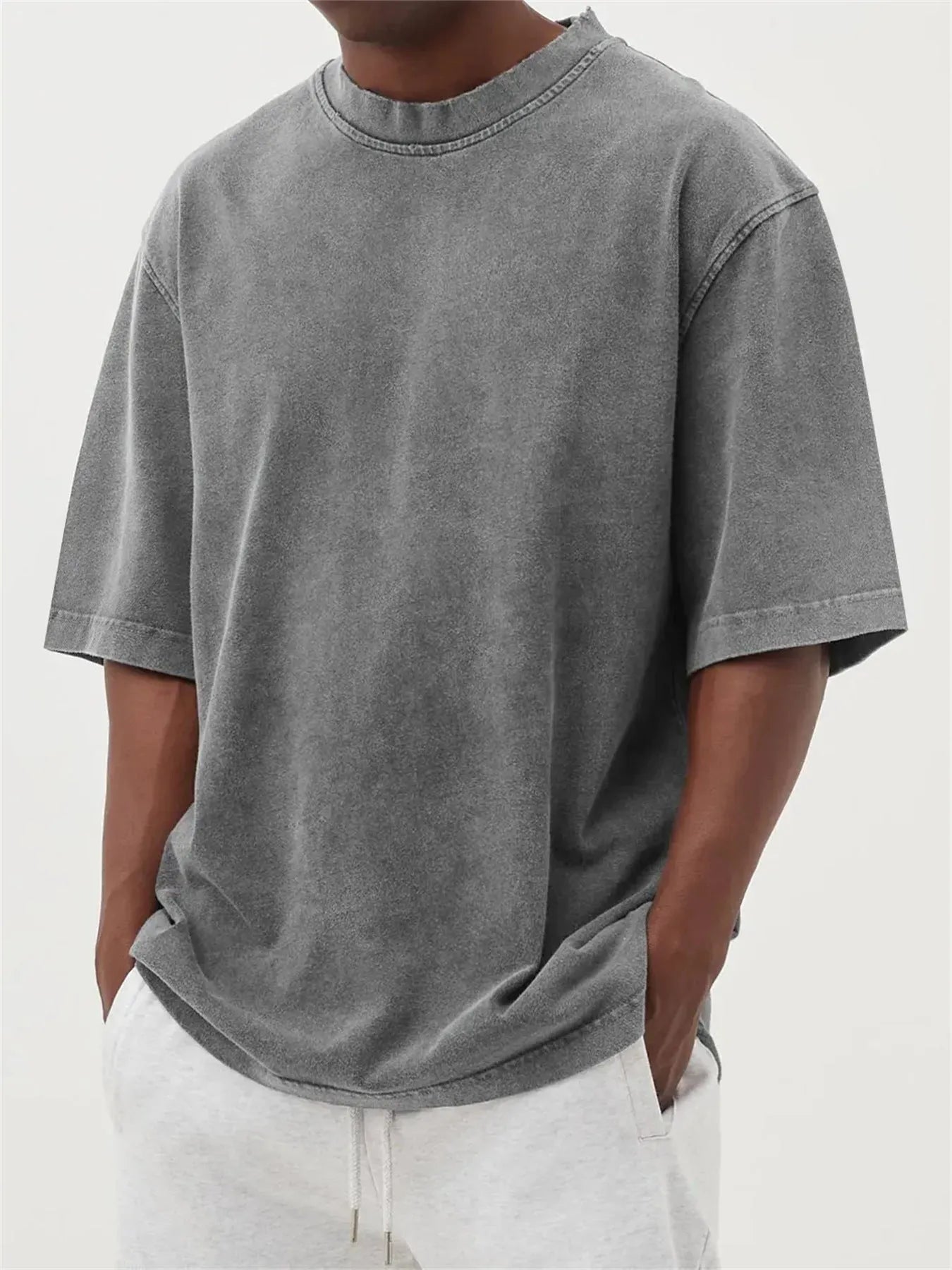 Man wearing a loose-fit, stone-washed grey t-shirt with a distressed solid colour finish and half sleeves.