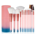 12 pink makeup brushes with synthetic hair bristles and plastic handles on a light surface