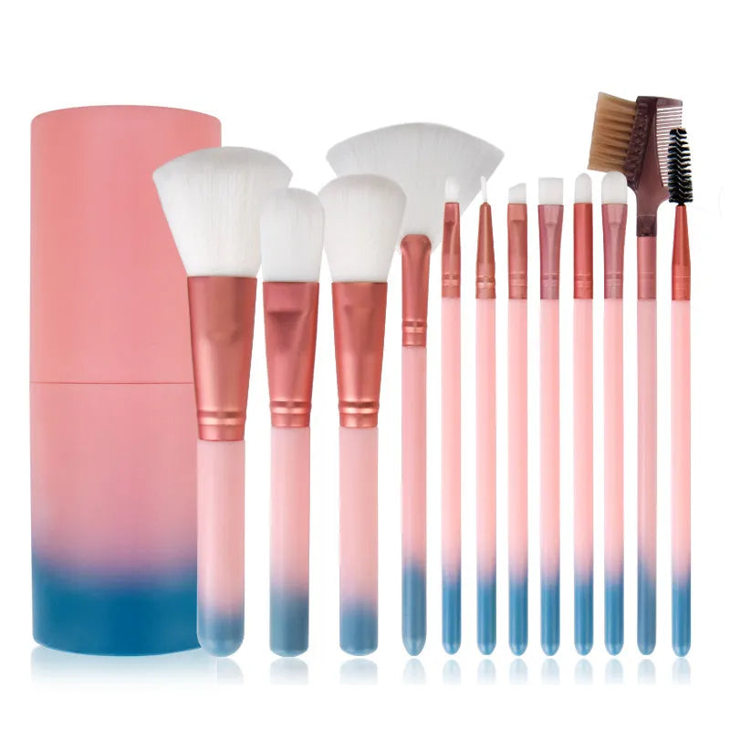 12 pink makeup brushes with synthetic hair bristles and plastic handles on a light surface