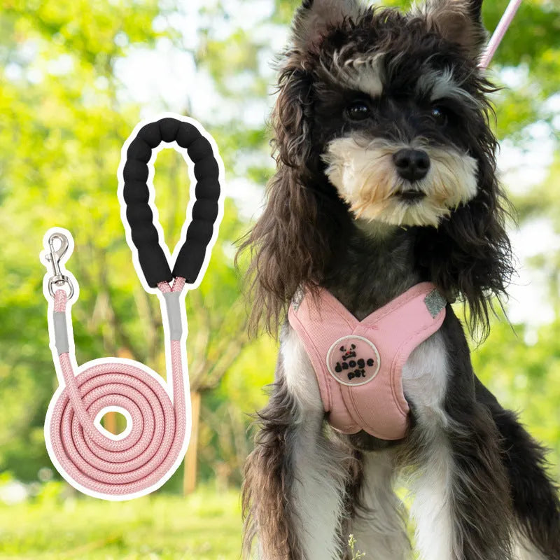 A pink dog vest harness connected to a matching hand-holding lead on a white background.