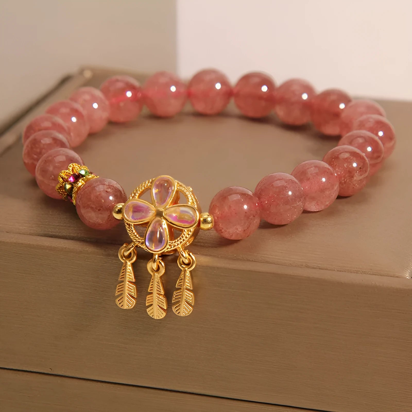 Women's strawberry quartz crystal bracelet with a four-leaf clover dream catcher ball pendant.