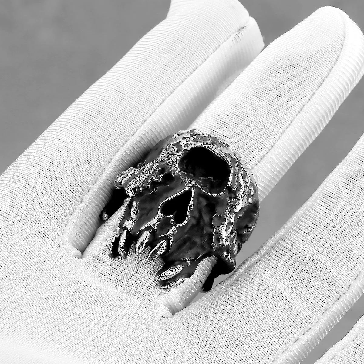 A silver-toned alloy ring with a raised one-eyed skull design on a black background.