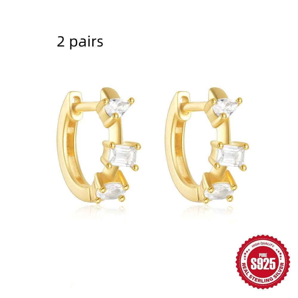 A pair of small, round, geometric stud earrings made of sterling silver with an electroplated finish.
