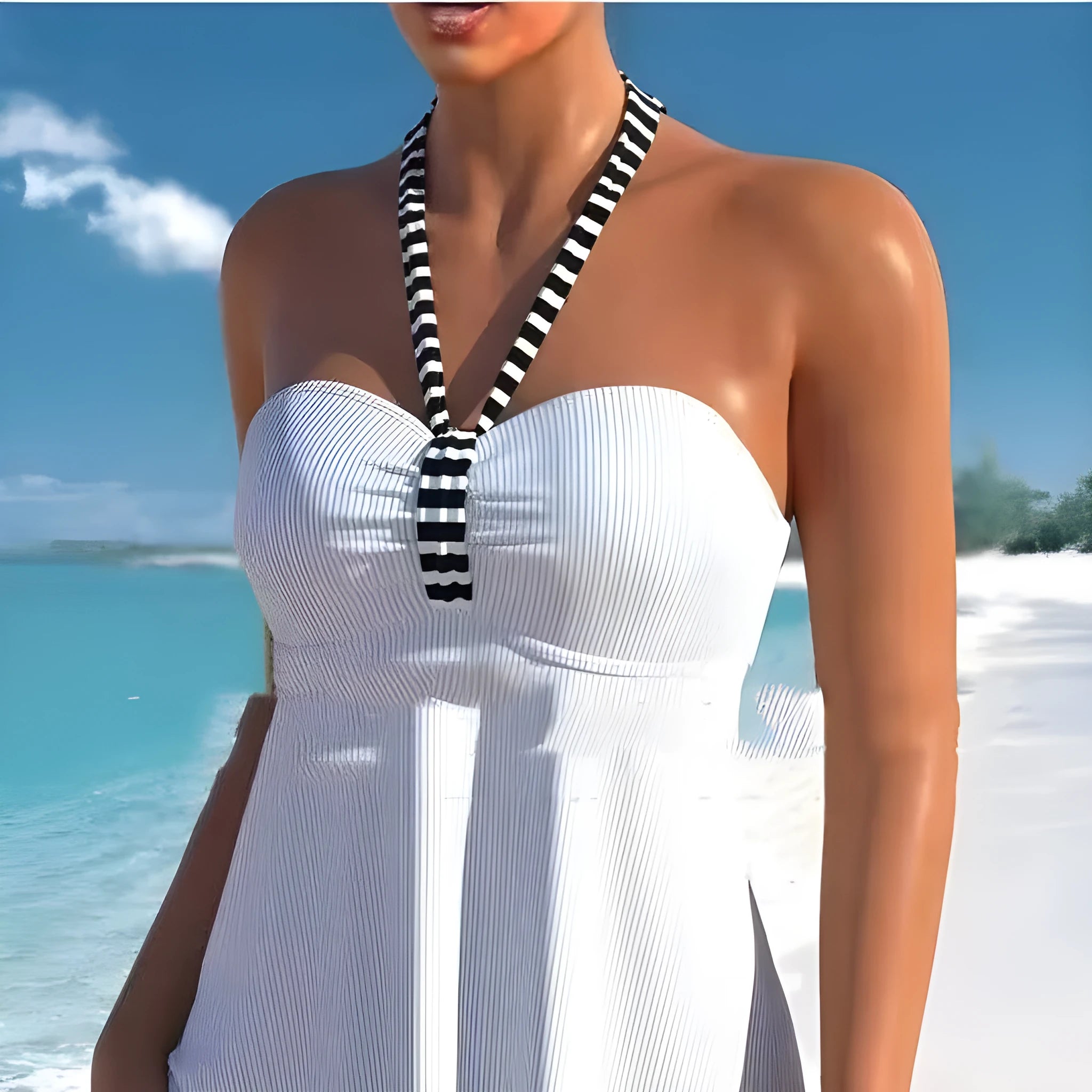 Woman modelling a black and white striped off-shoulder one-piece swimsuit on a beach.