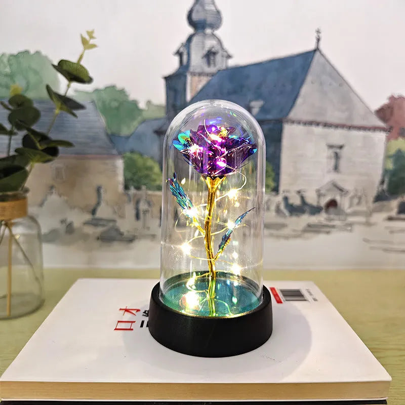 Small decorative table lamp with coloured LED lights illuminating plastic flowers under a glass dome.